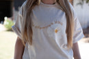 Beige t-shirt, white flower, the difference is jesus