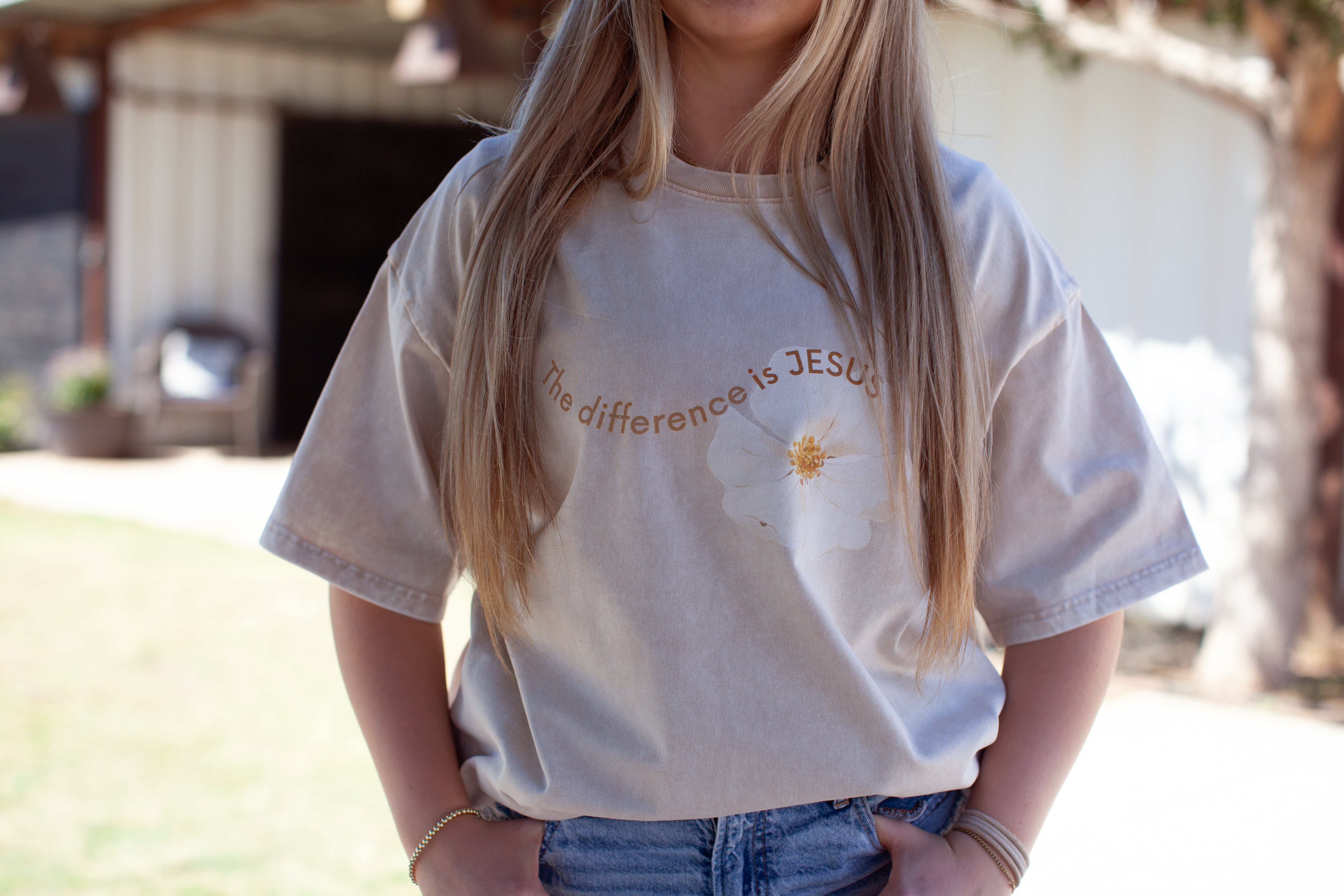 Beige t-shirt, white flower, the difference is jesus