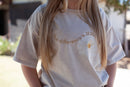Beige t-shirt, white flower, the difference is jesus